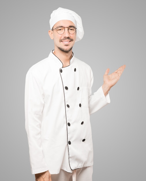 Sympathique jeune chef faisant un geste de bienvenue