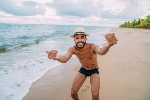 Sympathique jeune homme latino-américain invitant à venir au Brésil, confiant et souriant faisant un geste avec sa main, étant positif et amical