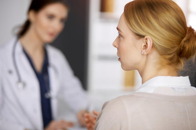 Sympathique souriante femme médecin et patiente discutant de l'examen de santé actuel dans une clinique ensoleillée. Service médical parfait à l'hôpital. Notion de médecine.