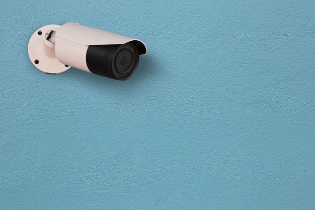 Photo système de caméra de surveillance blanche monté sur un mur de ciment bleu clair