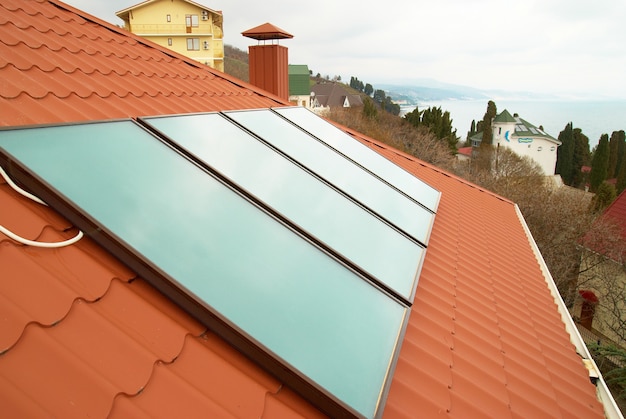 Système de chauffage solaire de l'eau (geliosystem) sur le toit de la maison rouge.