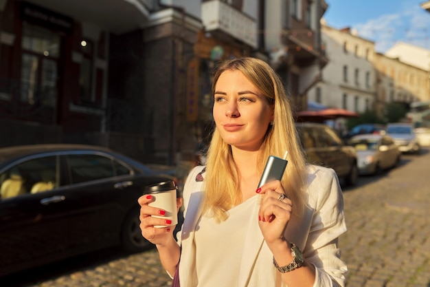 Système de chauffage d'une tasse de café en papier de tabac dans les mains d'une femme dans la rue de la ville