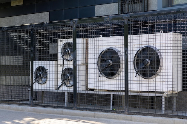 Système de compresseur de climatisation sur un bâtiment moderne protégé par une clôture métallique