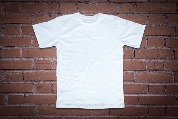 T-shirt blanc sur fond de mur de brique.