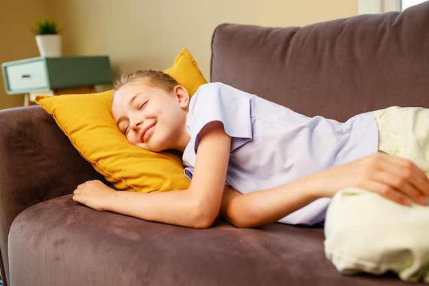 T-shirt en coton d'adolescente heureuse assis allongé sur un canapé à la maison