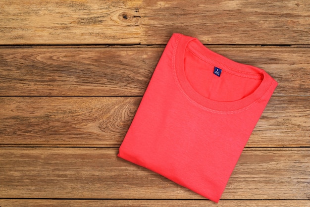 T-shirt en coton rouge posé sur fond en bois.