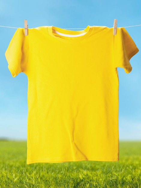 Un t-shirt de couleur jaune suspendu à une corde à linge