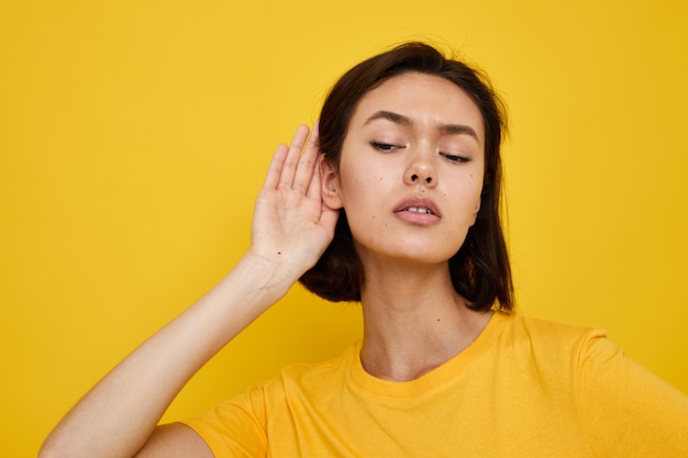 T-shirt jaune aux cheveux courts brune style d'été geste de la main fond jaune