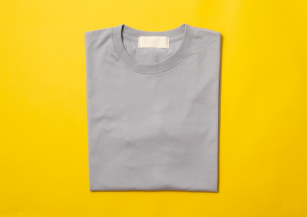 T-shirt plié gris isolé sur fond jaune.