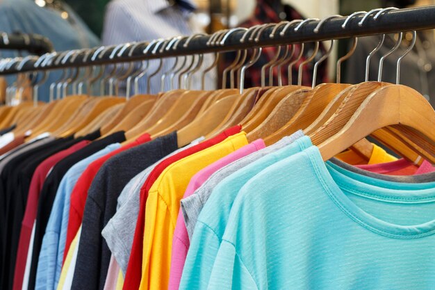 Photo t-shirts multicolores à manches longues sur des cintres en bois une vue latérale