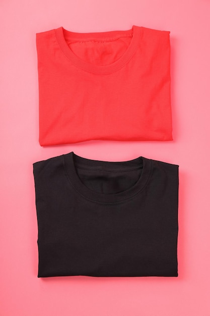 T-shirts noirs et rouges pliés sur fond rose