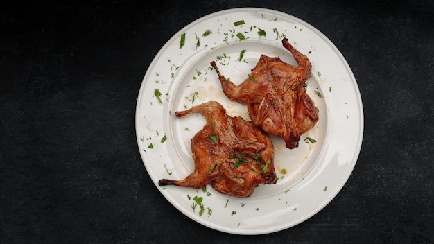 Tabac de poulet frit aux herbes sur une plaque blanche sur fond sombre