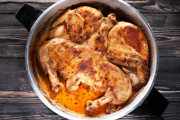 Tabac de poulet rôti grillé dans une poêle à frire sur fond de bois