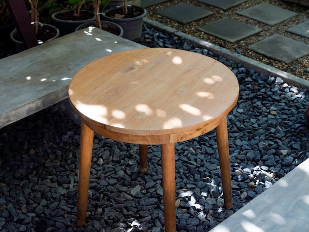 Table d'appoint ronde en bois vide avec siège en ciment simple sur sol en gravier près de la passerelle dans le jardin arrière, vue de dessus.