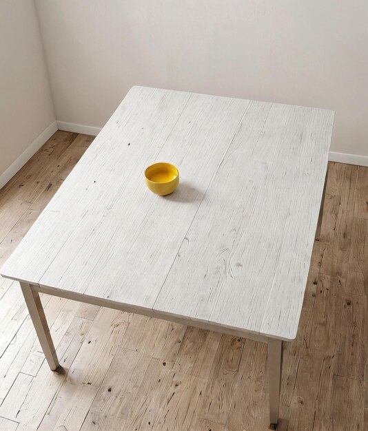 une table blanche avec un bol jaune sur le dessus