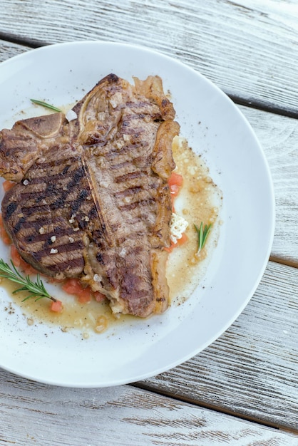 sur la table en bois assiette blanche avec steak et légumes grillés