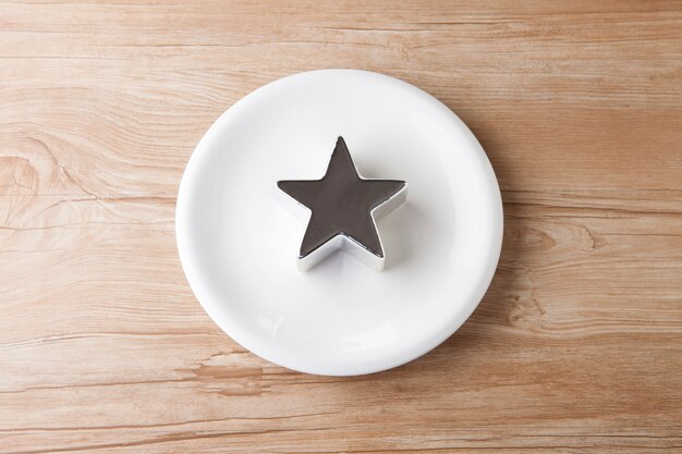 Table en bois avec assiettes blanches et rondes avec étoile d'argent