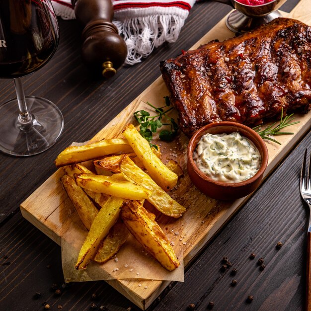 Photo une table en bois avec une bouteille de vin et une assiette de côtes levées et un bol de sauce.