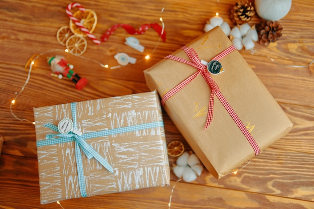 Table en bois avec des cadeaux de nouvel an et des coffrets cadeaux de décoration de Noël en papier d'emballage artisanal avec du blanc ...