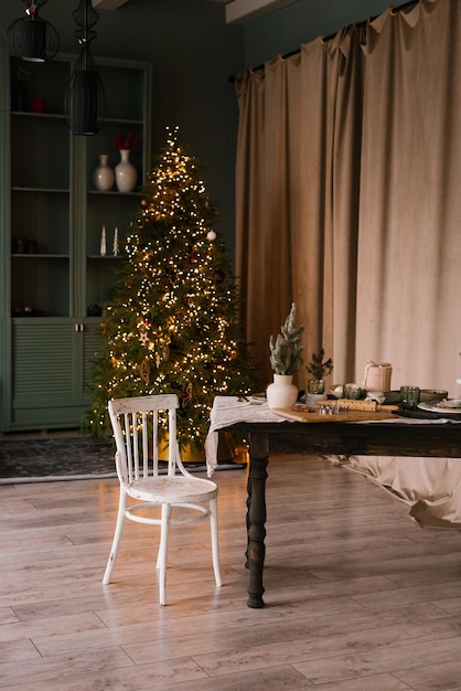Table en bois et chaise blanche dans le salon de Noël avec un arbre de Noël et des lumières