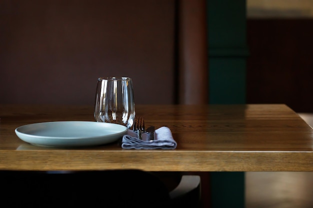 Table en bois décorée avec assiette vide verres fourchettes serviette vaisselle vierge table servie