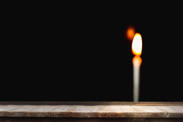 Table en bois devant une bougie lumineuse flou brillant noir