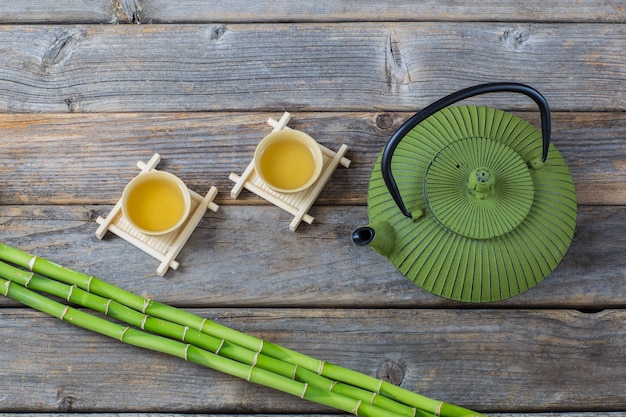 sur une table en bois, du bambou, du thé dans des bols et une théière