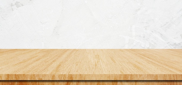 Une table en bois et un fond de mur blanc.