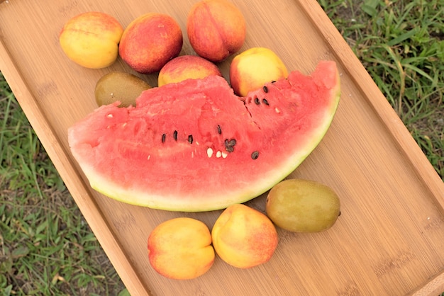 Table en bois avec des fruits sur un fond d&#39;herbe verte.