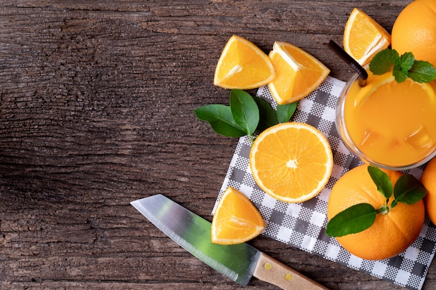 Table en bois avec des fruits d’orange en tranches et un verre de jus d’orange.