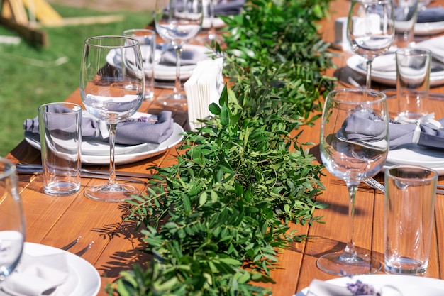 Table en bois joliment décorée dans un café d'été en plein air. Décoration de table branche verte et fleurs fraîches