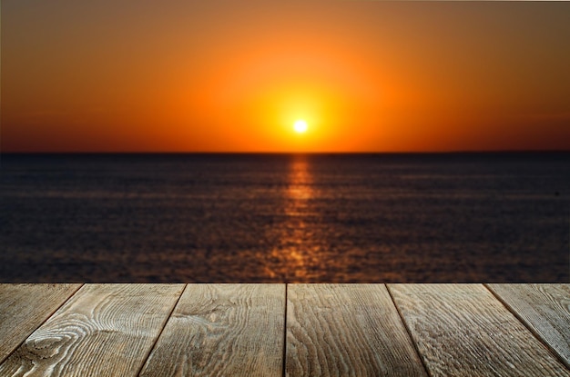 Une table en bois marron vide Arrière-plan flou avec coucher de soleil sur la mer