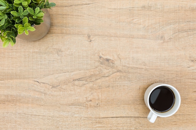 Table en bois minimaliste avec café et une petite plante.