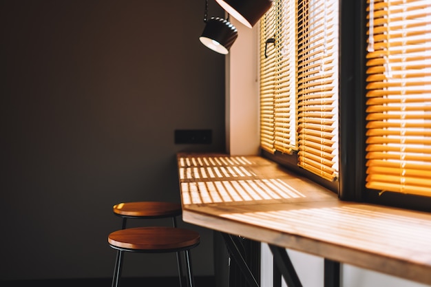 Table en bois moderne sur la cuisine près de la grande fenêtre avec rideau