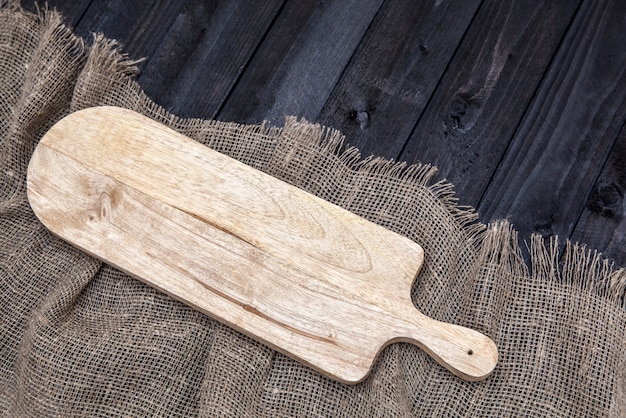 Table en bois noir avec nappe de jute et planche à découper, vue de dessus