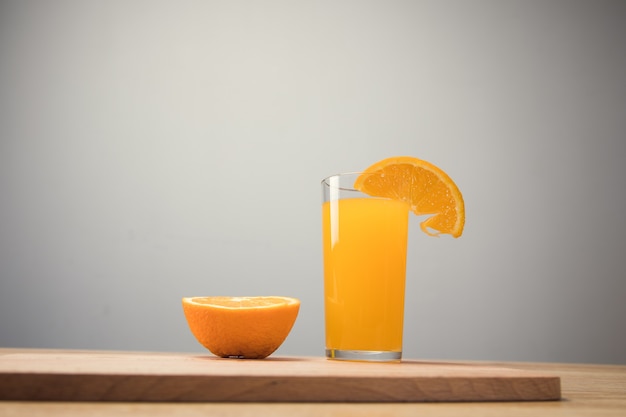 Sur une table en bois une orange et un verre avec une boisson