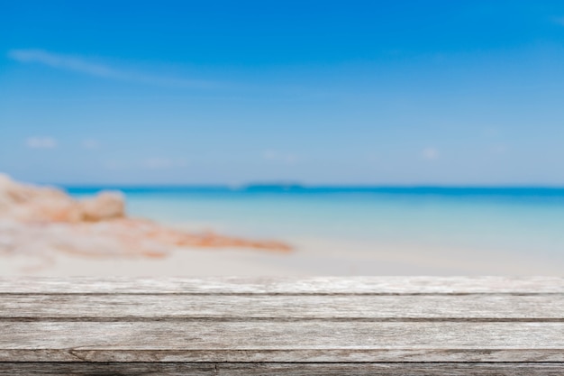Table en bois et plage d&#39;été floue avec mer bleue et ciel
