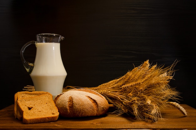 Table en bois avec un pot de lait, du pain de seigle et une gerbe