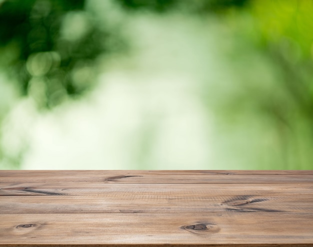 Table en bois pour la décoration intérieure ou l'affichage publicitaire sur fond vert bokeh