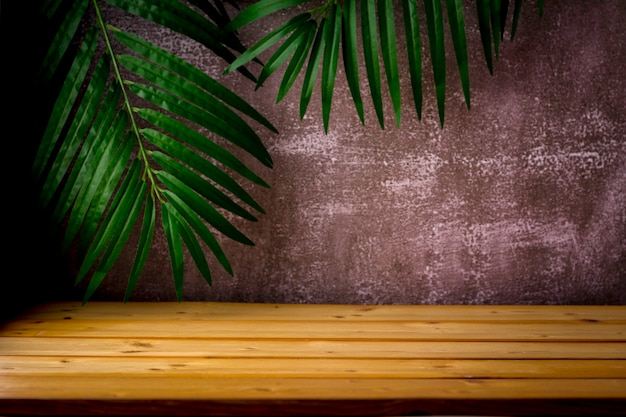 table en bois pour la présentation et la présentation du produit, des feuilles de palmier et un fond sombre et robuste