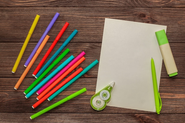 Sur une table en bois se trouvent des feutres multicolores