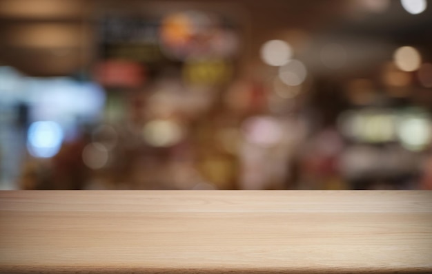 Une table en bois sombre vide devant l'arrière-plan abstrait bokeh flou du restaurant peut être utilisée pour l'affichage ou le montage de vos produits Maquette pour l'espace