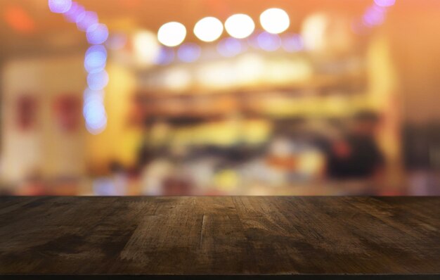 Une table en bois sombre vide devant un fond bokeh flou abstrait du restaurant peut être utilisée pour l'affichage ou le montage de vos produits.