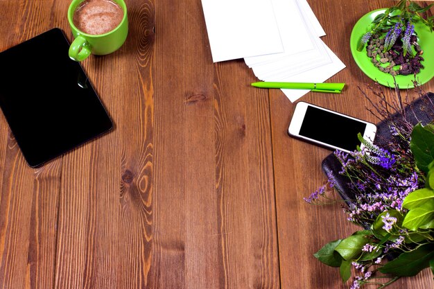 Une table en bois avec un stylo vert, un stylo vert, un téléphone, un stylo vert, un stylo vert et un stylo vert dessus.