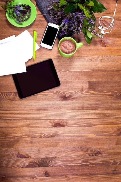 Photo une table en bois avec une tablette, un téléphone et d'autres objets dessus.