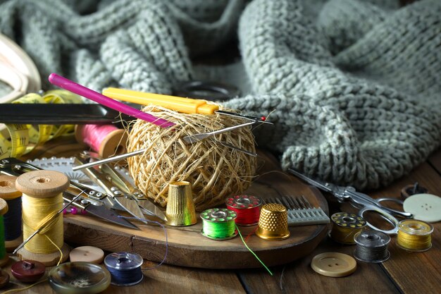 Une table en bois avec un tas de fournitures de couture, y compris une aiguille, du fil et d'autres fournitures de couture.