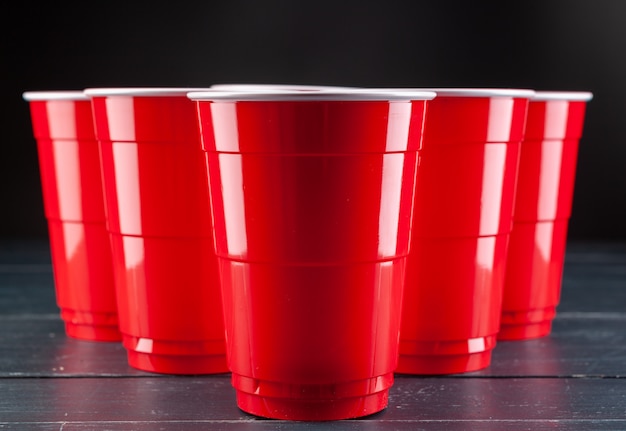 Table en bois avec des tasses rouges et une boule pour Beer Pong