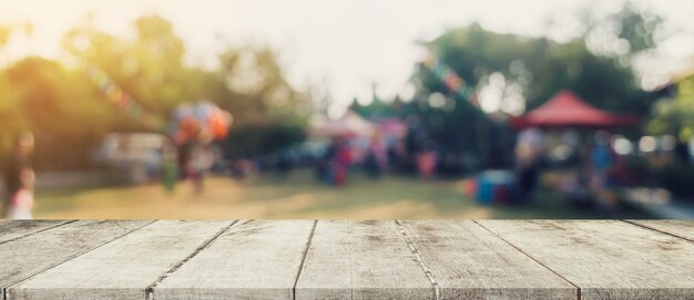 Table en bois vide et bokeh défocalisé et arrière-plan flou des arbres de jardin au soleil.