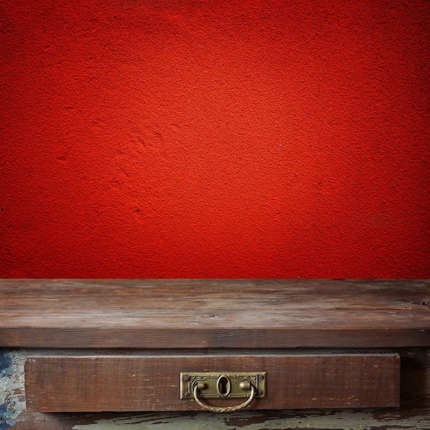 Table en bois vide contre un mur rouge.