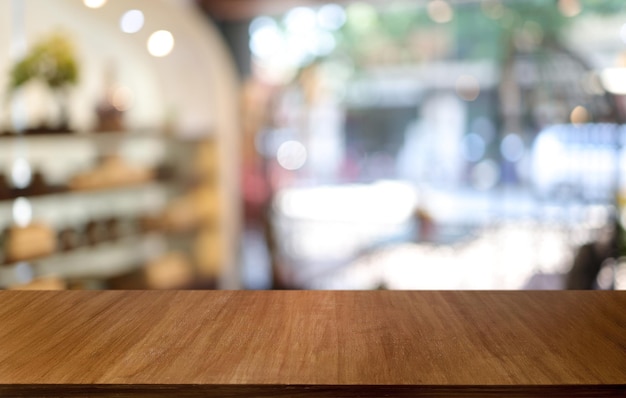 La table en bois vide devant l'arrière-plan flou abstrait du café peut être utilisée pour l'affichage ou le montage de vos produits Maquette pour l'affichage du produit